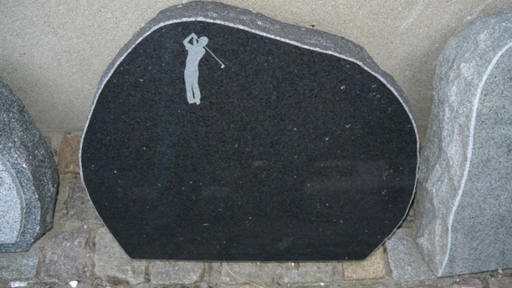 Sort natursten mindesten med motiv af golfspiller